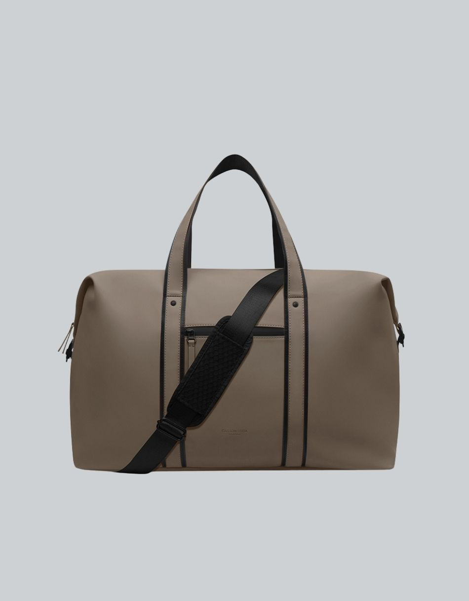 Bolso de viaje Däsh 2.0 M Café Oscuro, vista frontal con asas y correa negra